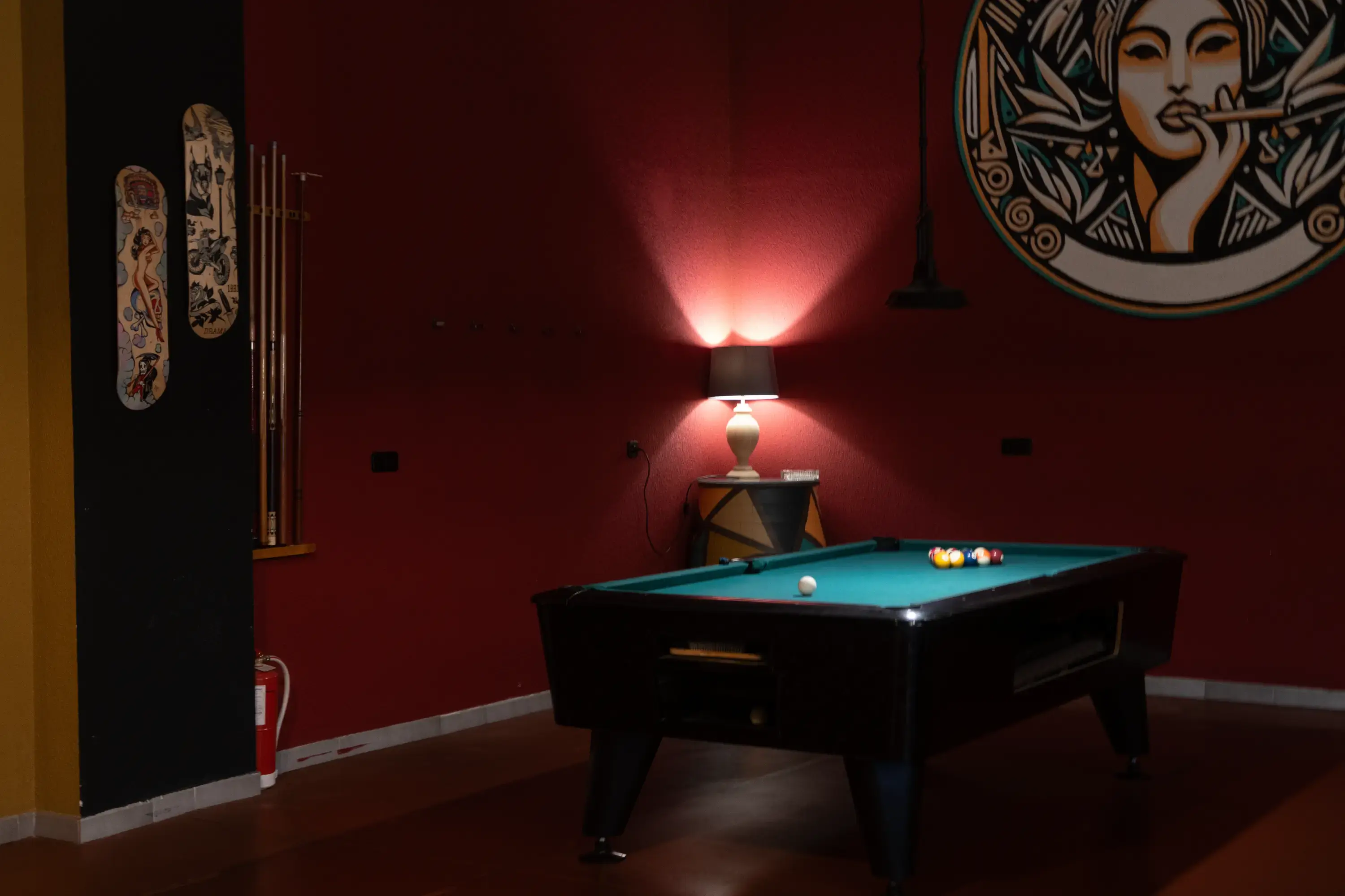 Sala de billar de la asociación cannábica IBOGA, con el mural del club en la pared roja